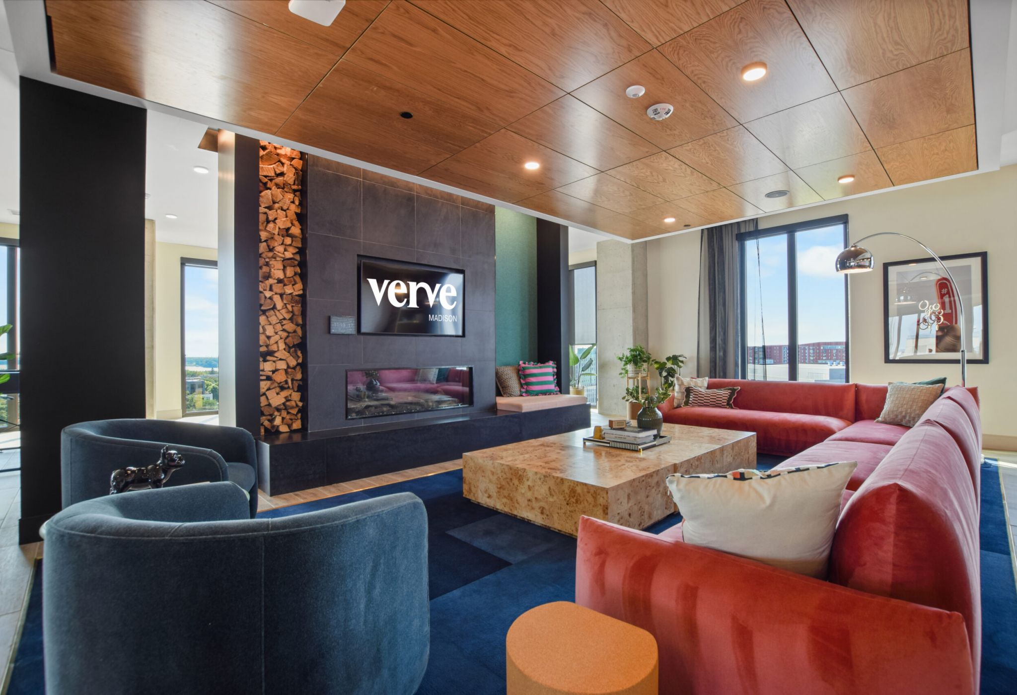 Modern living room with a large red sectional sofa, round coffee table, and wall-mounted TV next to a fireplace.