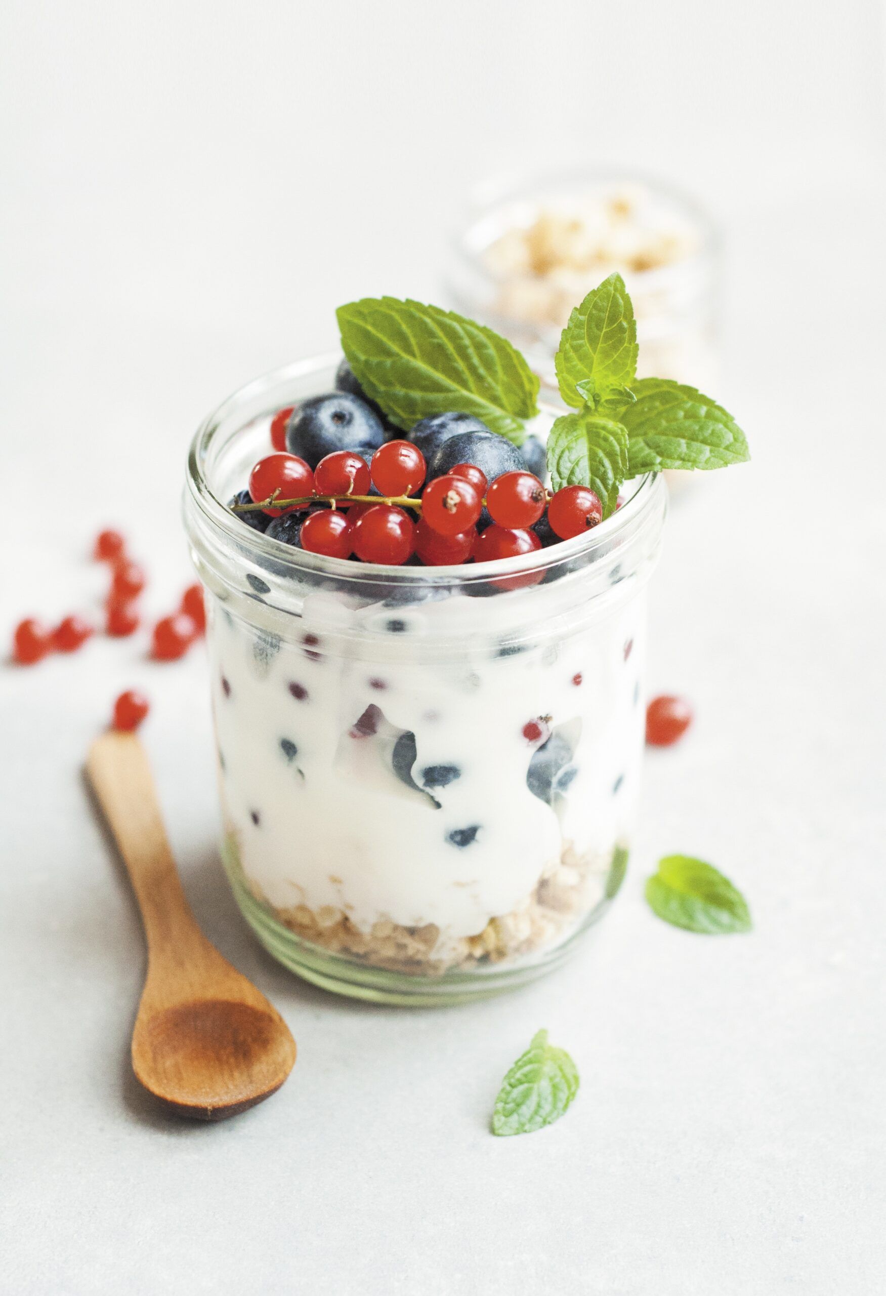 Glass jar full of yogurt and topped with various berries
