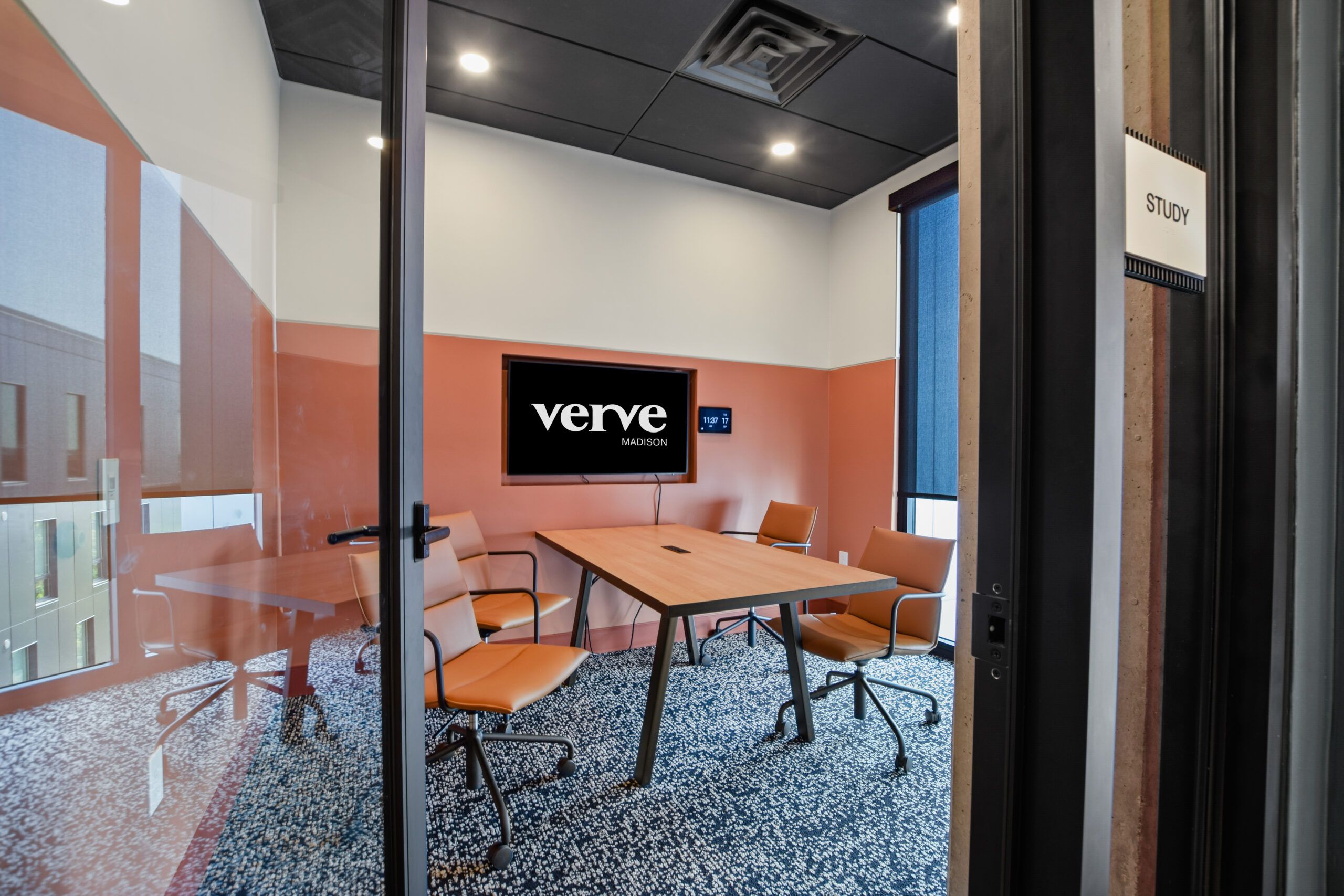 Modern study room with a wooden table, four chairs, and a screen displaying "Verve." Room labeled "Study.