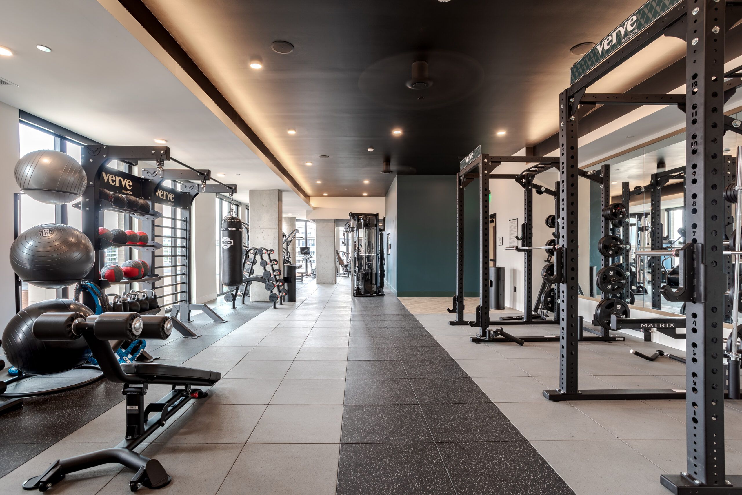 A modern gym with weight racks, exercise machines, and fitness balls under bright ceiling lights.